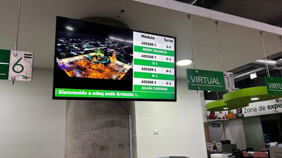 Monitor colgante de gran formato mostrando claramente los módulos, el turno en curso y los nombres de los asesores disponibles