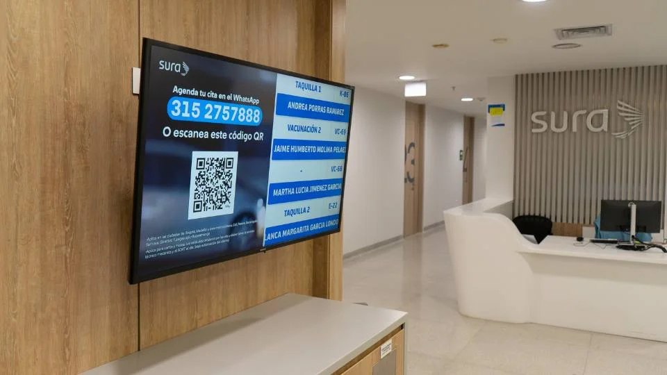 Écran à la réception affichant un grand code QR pour la prise de rendez-vous à distance via WhatsApp